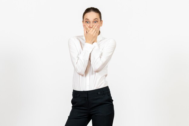 Vooraanzicht jonge vrouw in elegante witte blouse met geschokt gezicht op een witte achtergrond vrouw kantoorbaan dame vrouwelijke werknemer