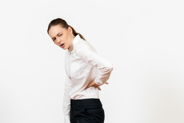 Vooraanzicht jonge vrouw in elegante witte blouse met rugpijn op witte achtergrond vrouw kantoor baan vrouwelijke werknemer lady