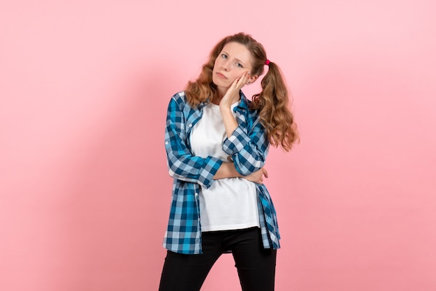 Vooraanzicht jonge vrouw in geruit overhemd poseren op roze achtergrond jeugd vrouw emoties model kind kleur