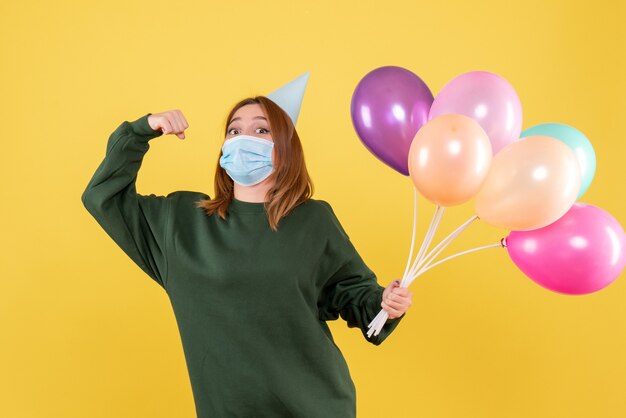 Vooraanzicht jonge vrouw in masker met kleurrijke ballonnen