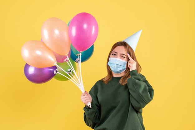 Vooraanzicht jonge vrouw in masker met kleurrijke ballonnen