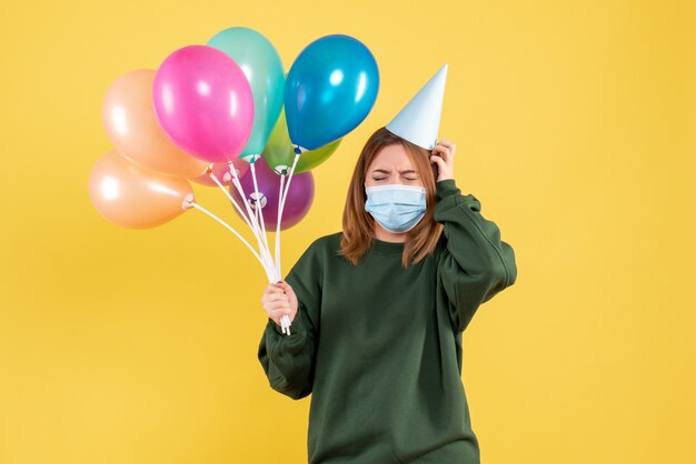 Vooraanzicht jonge vrouw in masker met kleurrijke ballonnen