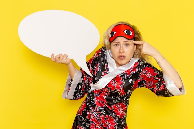 Vooraanzicht jonge vrouw in nacht gewaad met groot wit bord op gele bureau slaap nacht bed model kleur