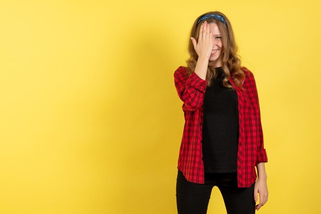 Vooraanzicht jonge vrouw in rood geruit overhemd poseren en glimlachen op gele achtergrond model meisjes vrouw emoties menselijke vrouwelijke kleur