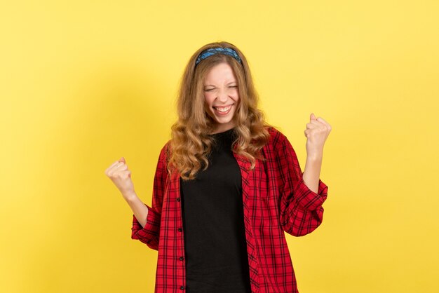 Vooraanzicht jonge vrouw in rood geruit overhemd poseren met gelukkige gevoelens op gele achtergrond menselijke emotie kleur model vrouw