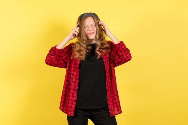 Vooraanzicht jonge vrouw in rood geruit overhemd poseren met pijnlijke uitdrukking op gele achtergrond menselijke emotie kleur model vrouw