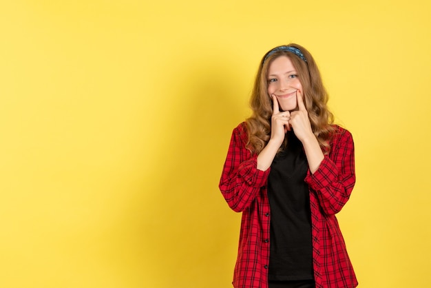 Vooraanzicht jonge vrouw in rood geruit overhemd staande op gele achtergrond meisjes kleur model menselijke vrouw