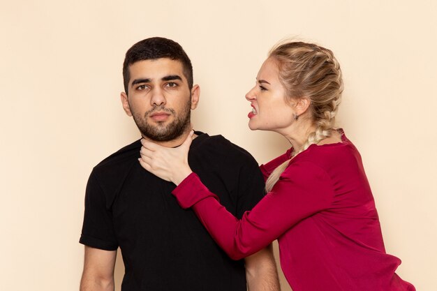 Vooraanzicht jonge vrouw in rood shirt chocking man op de crème ruimte foto emotie model geweld