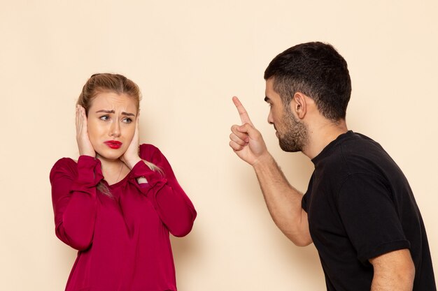 Vooraanzicht jonge vrouw in rood shirt lijdt aan fysieke bedreigingen en geweld op de crème ruimte vrouw doek foto huiselijk geweld