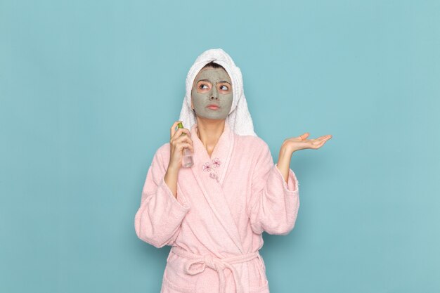 Vooraanzicht jonge vrouw in roze badjas na douche bedrijf spray op blauwe muur schoonmaken schoonheid schoon water zelfzorg crème douche