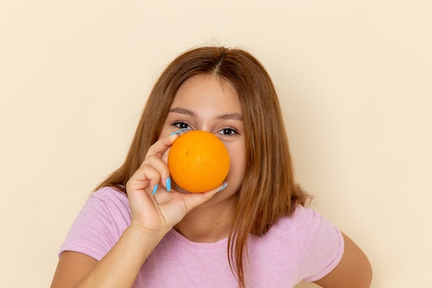 Vooraanzicht jonge vrouw in roze t-shirt en spijkerbroek met sinaasappel