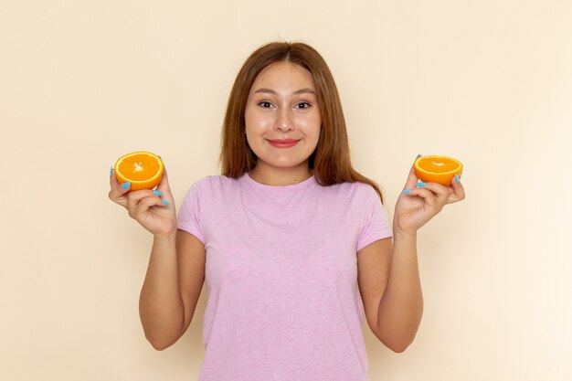 Vooraanzicht jonge vrouw in roze t-shirt en spijkerbroek oranje met glimlach te houden