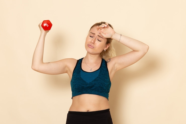Gratis Foto vooraanzicht jonge vrouw in sport outfit met rode halters op wit bureau sport lichaam gezondheid schoonheid training vrouw