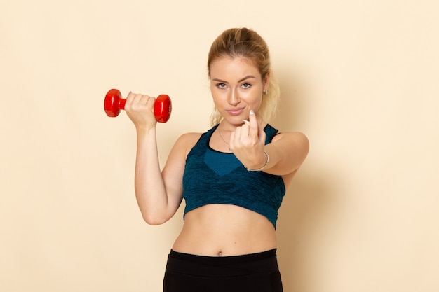 Vooraanzicht jonge vrouw in sport outfit met rode halters op witte muur gezondheid sport lichaam schoonheid training