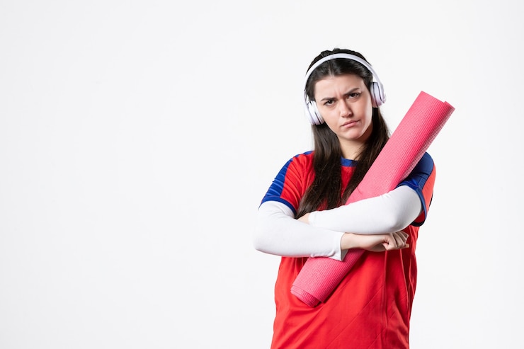 Gratis Foto vooraanzicht jonge vrouw in sportkleding met yogamat luisteren naar muziek witte muur