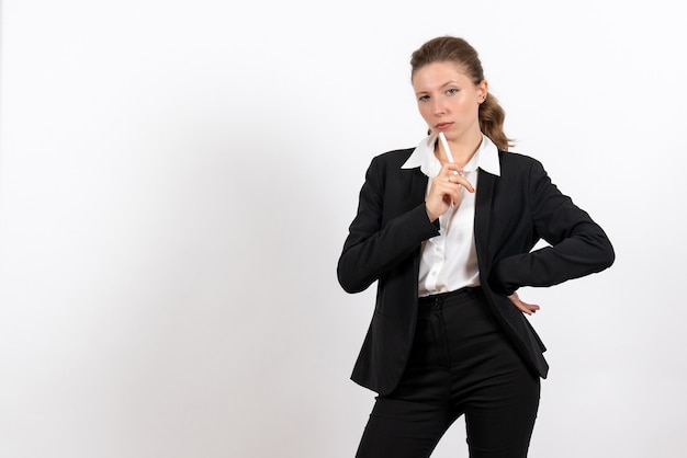 Vooraanzicht jonge vrouw in strikte klassieke pak met pen op witte achtergrond vrouw baan bedrijf vrouwelijk werk kostuum