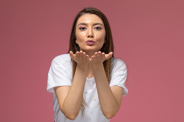 Vooraanzicht jonge vrouw in wit overhemd luchtkussen verzenden op roze muur, kleur model vrouw pose