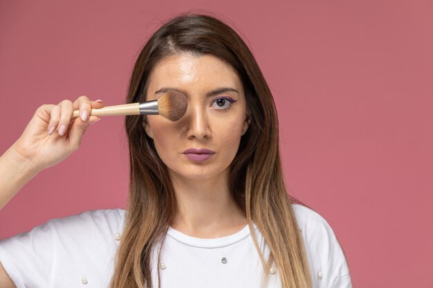 Vooraanzicht jonge vrouw in wit overhemd met make-up borstel op roze, model vrouw pose meisje schoonheid