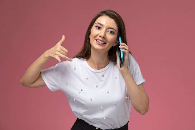 Vooraanzicht jonge vrouw in wit overhemd praten aan de telefoon lachend op de roze muur