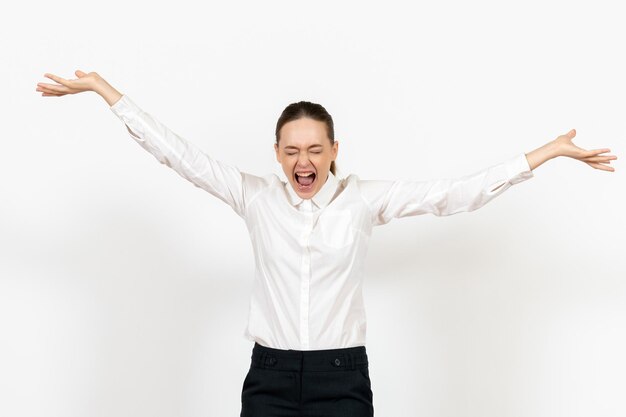 Vooraanzicht jonge vrouw in witte blouse die boos bestanden op de witte achtergrond gooit vrouwelijke emotie die kantoorbaan voelt