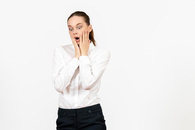 Vooraanzicht jonge vrouw in witte blouse met geschokt gezicht op witte achtergrond kantoorbaan vrouwelijke emotie gevoel model