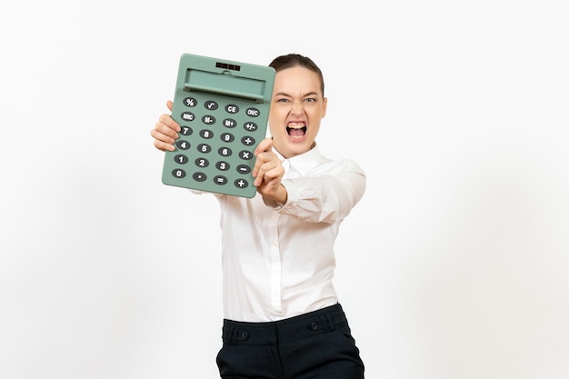 Vooraanzicht jonge vrouw in witte blouse met grote rekenmachine op wit bureau kantoor vrouwelijke werknemer emotie gevoel baan wit