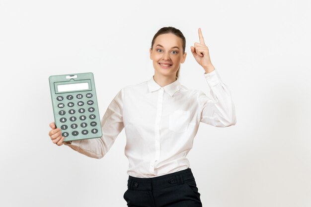 Vooraanzicht jonge vrouw in witte blouse met grote rekenmachine op witte achtergrond kantoor vrouwelijke werknemer emotie gevoel baan white