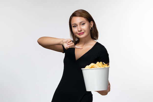 Vooraanzicht jonge vrouw in zwart shirt met chips en poseren op een witte ondergrond