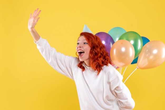 Gratis foto vooraanzicht jonge vrouw kleurrijke ballonnen achter haar rug kleur nieuwjaar