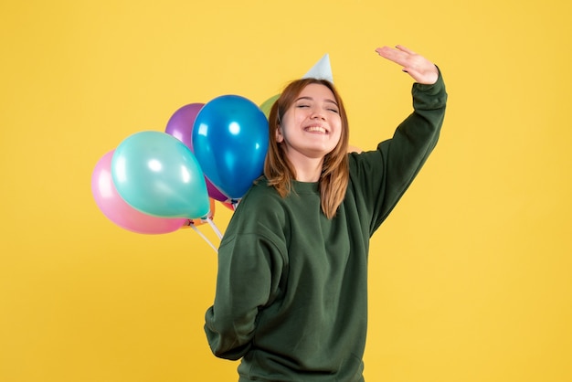 Vooraanzicht jonge vrouw kleurrijke ballonnen achter haar rug verbergen