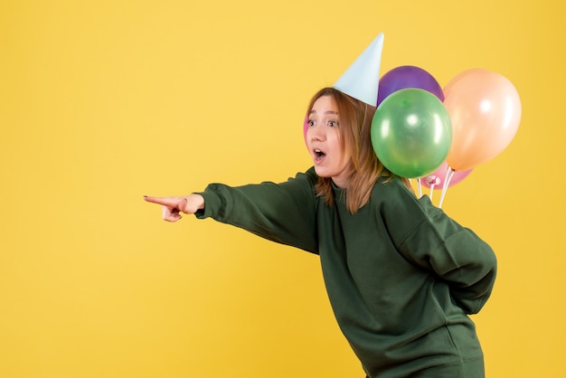 Vooraanzicht jonge vrouw kleurrijke ballonnen verbergen