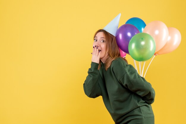 Vooraanzicht jonge vrouw kleurrijke ballonnen verbergen