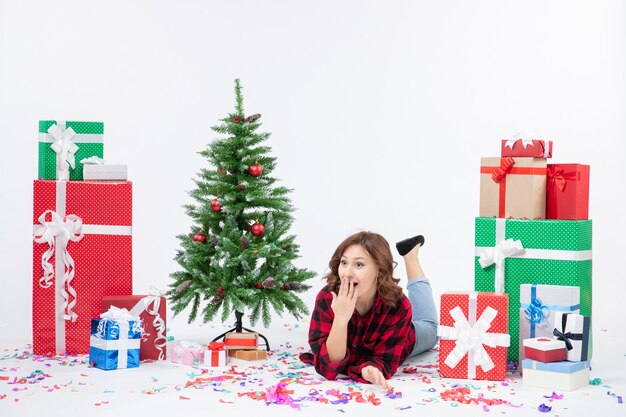 Vooraanzicht jonge vrouw leggen rond kerstcadeaus en vakantieboom op witte achtergrond xmas nieuwjaar cadeau kleur sneeuw emotie