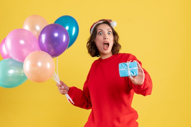 Vooraanzicht jonge vrouw met ballonnen en weinig aanwezig op gele kerstvakantie nieuwe jaar emotie kleur vrouw