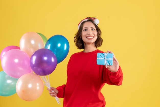 Vooraanzicht jonge vrouw met ballonnen en weinig aanwezig op gele kerstvakantie nieuwe jaar emotie kleur vrouw