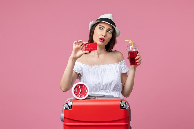 Vooraanzicht jonge vrouw met bankkaart en sap op vakantie op de roze muur reis reis zomer vrouw