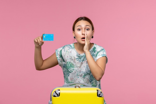 Vooraanzicht jonge vrouw met bankkaart met gele vakantietas op de lichtroze muur rust vlucht reis vliegtuig vrouw