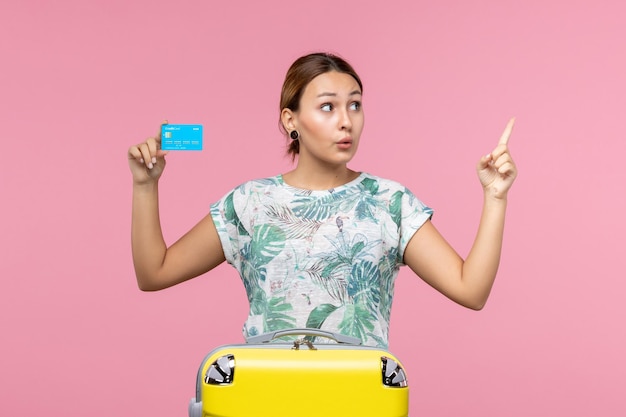 Vooraanzicht jonge vrouw met bankkaart met gele vakantietas op roze muurvliegtuig vakantie vlucht reis vrouw rust