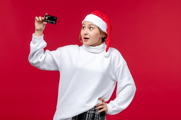 Vooraanzicht jonge vrouw met bankkaart op rode achtergrond