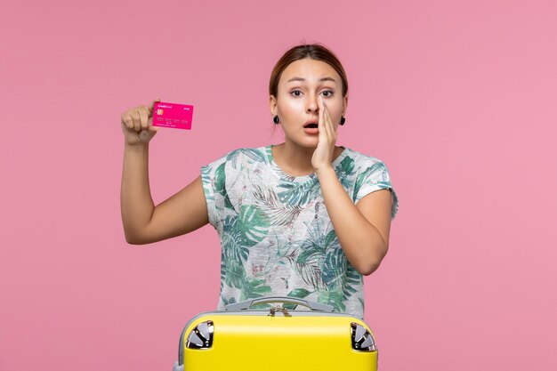 Vooraanzicht jonge vrouw met bankkaart op vakantie en fluisteren op roze muur zomerrust reis vakantie vrouw