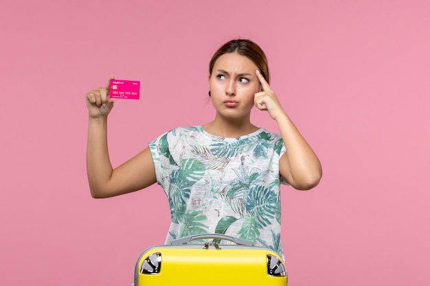 Vooraanzicht jonge vrouw met bankkaart op vakantie op roze muur zomer rust reis vakantie vrouw