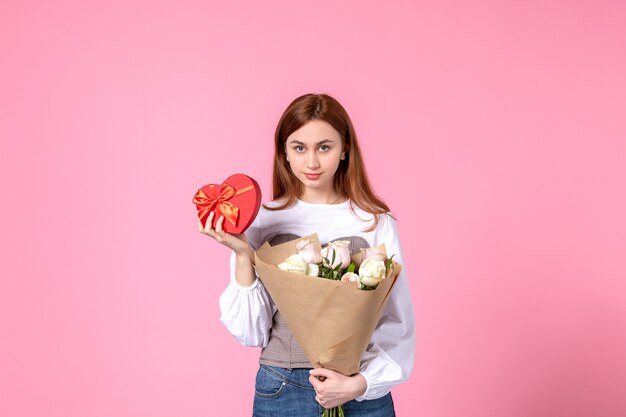 Vooraanzicht jonge vrouw met bloemen en heden als de daggift van de vrouw op roze achtergrond steeg horizontaal maart vrouwelijke datum liefde sensuele gelijkheid