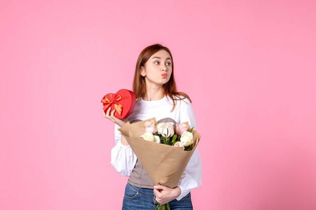 Vooraanzicht jonge vrouw met bloemen en heden als de daggift van de vrouw op roze achtergrond steeg horizontale maart vrouwelijke datum vrouw sensuele gelijkheid