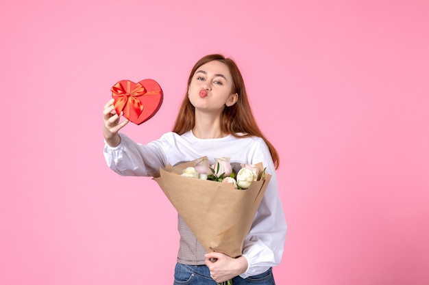 Vooraanzicht jonge vrouw met bloemen en heden als vrouwendag cadeau op roze achtergrond horizontale maart vrouw liefde sensuele vrouwelijke datum roos