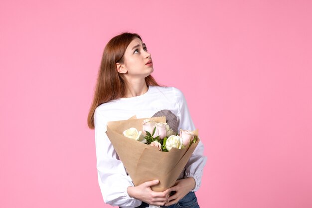 Vooraanzicht jonge vrouw met boeket van mooie rozen op pinks