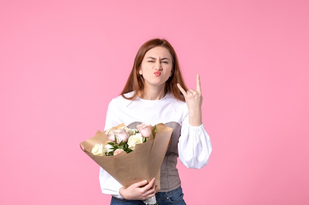 Vooraanzicht jonge vrouw met boeket van mooie rozen op roze