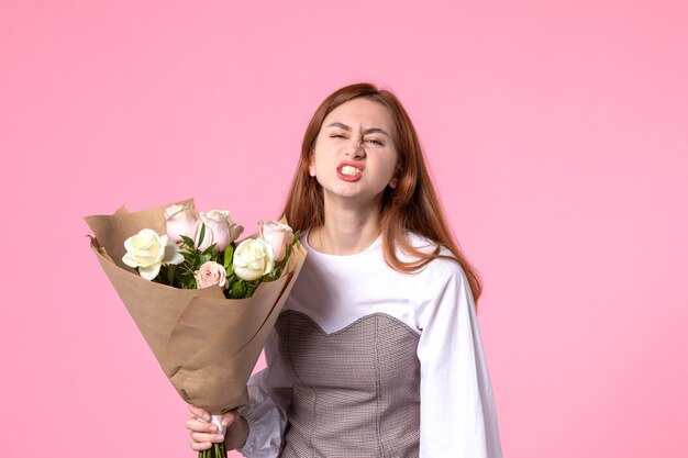 Vooraanzicht jonge vrouw met boeket van mooie rozen op roze