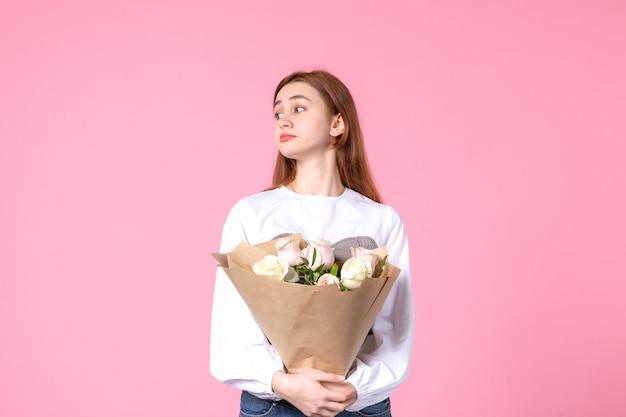 Vooraanzicht jonge vrouw met boeket van mooie rozen op roze