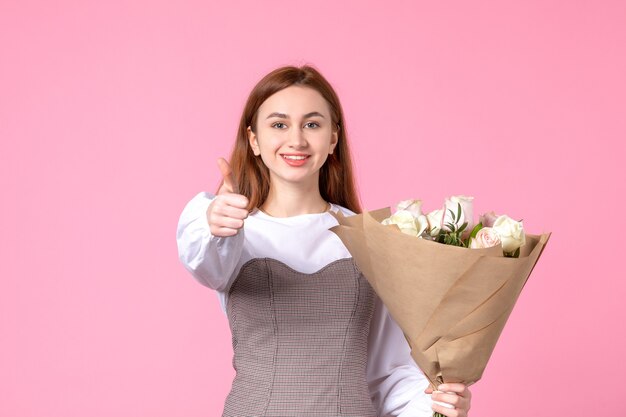 Vooraanzicht jonge vrouw met boeket van mooie rozen op roze