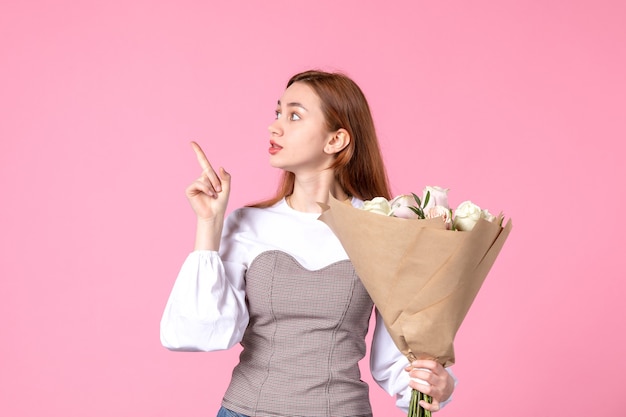 Vooraanzicht jonge vrouw met boeket van mooie rozen op roze